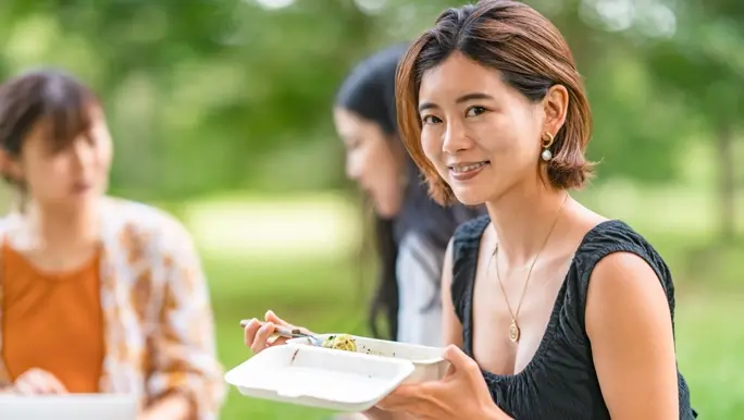 Woman eating a low FODMAP lunch in the park with friends
