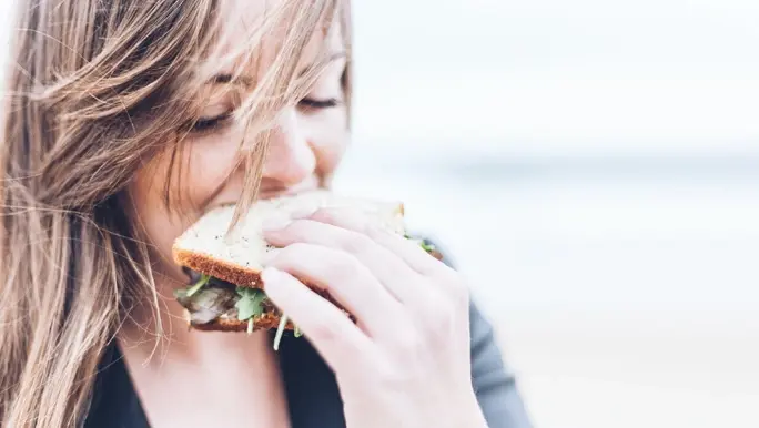 Young woman eating a sandwich made with low FODMAP bread