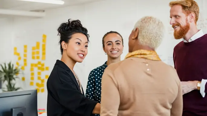 Colleagues standing in a small group discussing something while working at an office.