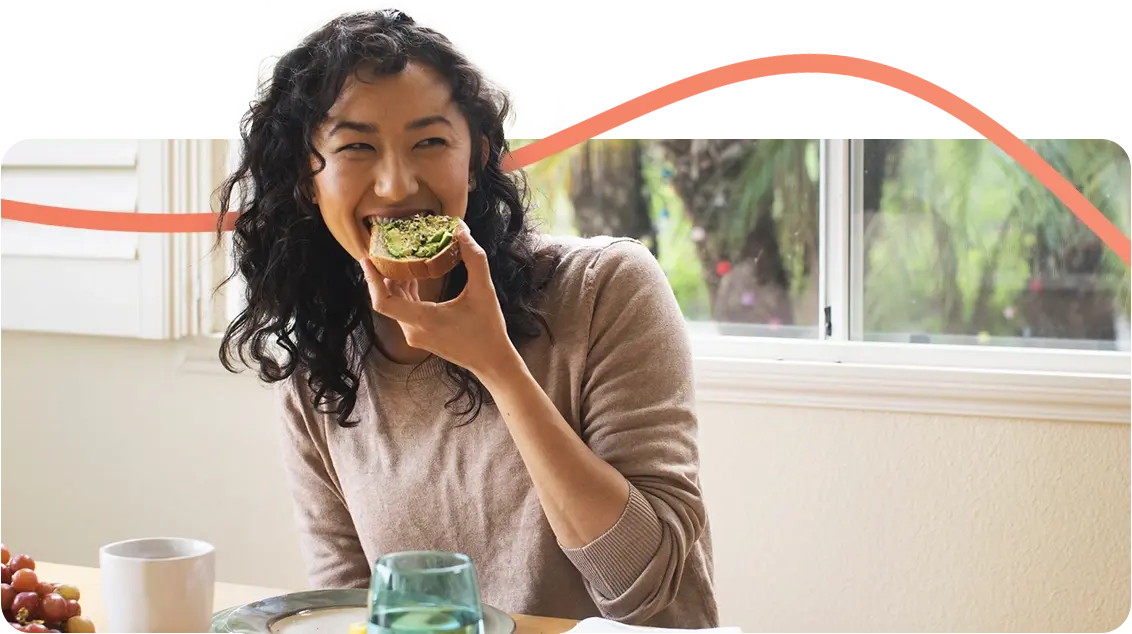 Happy woman eating avocado on toast