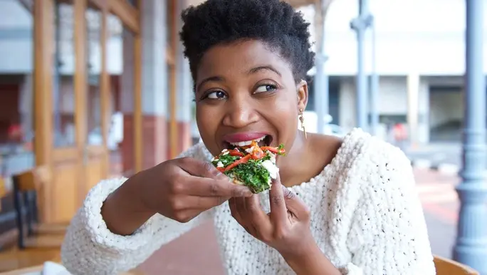 Woman eating vegetarian pizza for lunch at an outdoor cafe