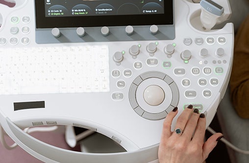 A hand pressing a button on a sonography machine.