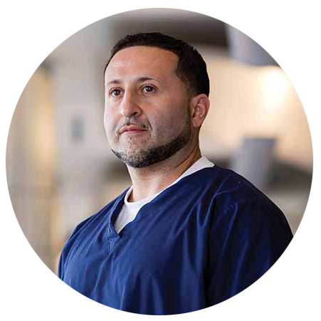 Round head and shoulders photo of a male R.T. in dark blue scrubs 
