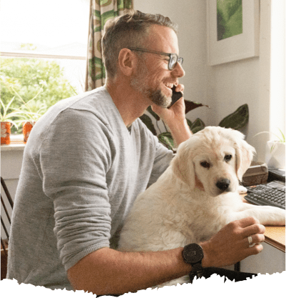 A man holding his dog while talking to someone on the phone.