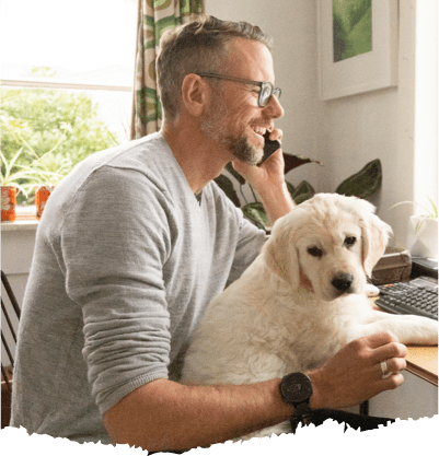 A man holding his dog while talking to someone on the phone. A man holding his dog while talking to someone on the phone.