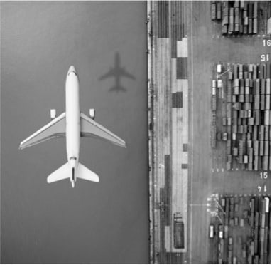 An airplane flying over a cargo dock, showcasing the way how moving goods can be done.