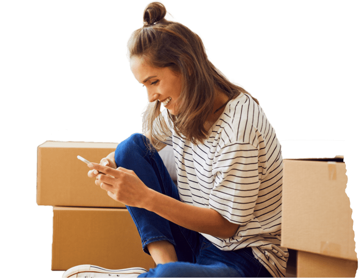 A woman sitting on the floor surrounded by boxes, using her phone, and preparing for moving day.