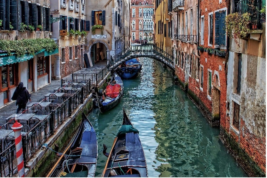 Gondolas glide through the water in the canals in Venice, Italy.