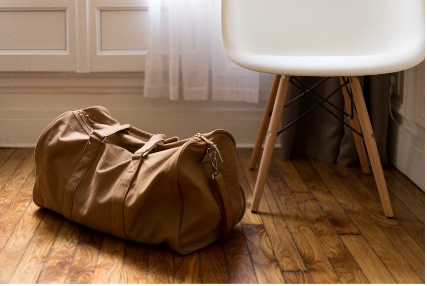 A brown suitcase sits on the floor, packed for a move to Iceland with Atlas® International.