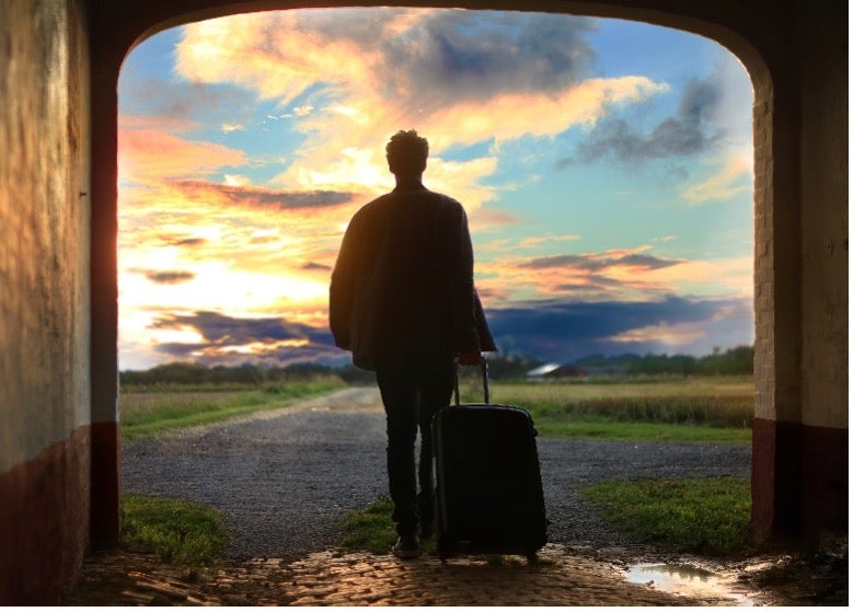 A man stands in an archway with his suitcase before his individual move to Italy with Atlas International. 