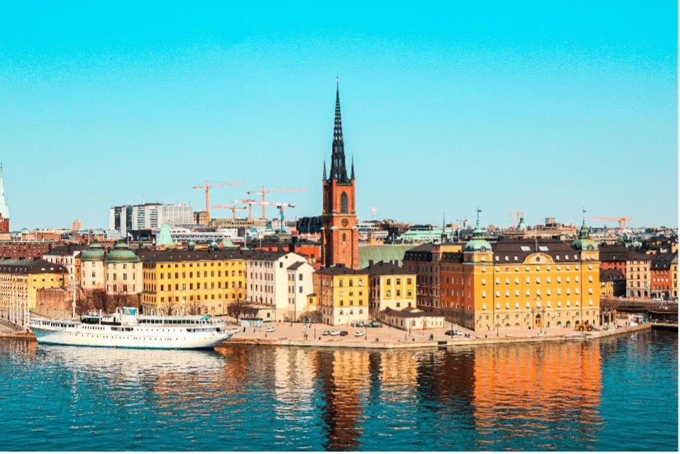 Stockholm, Sweden sits on the water, its buildings visible against a blue sky.