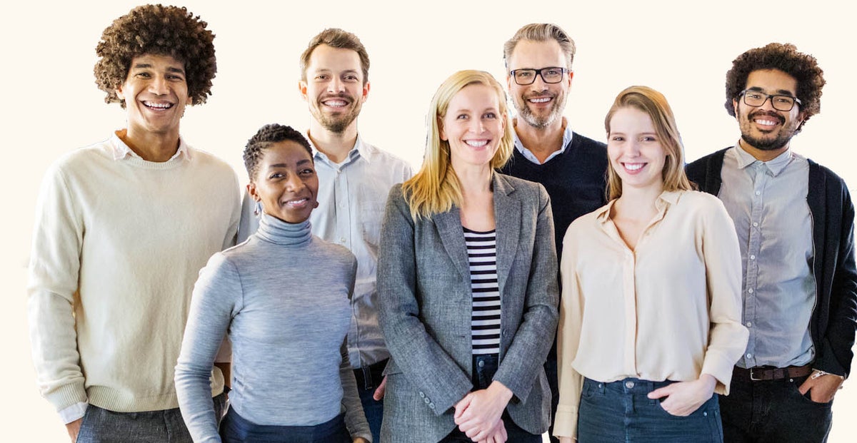 Several people gathered in front of a white background, striking a pose as a team.