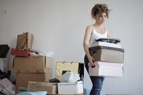 Woman carrying stack of cardboard boxes for relocation.