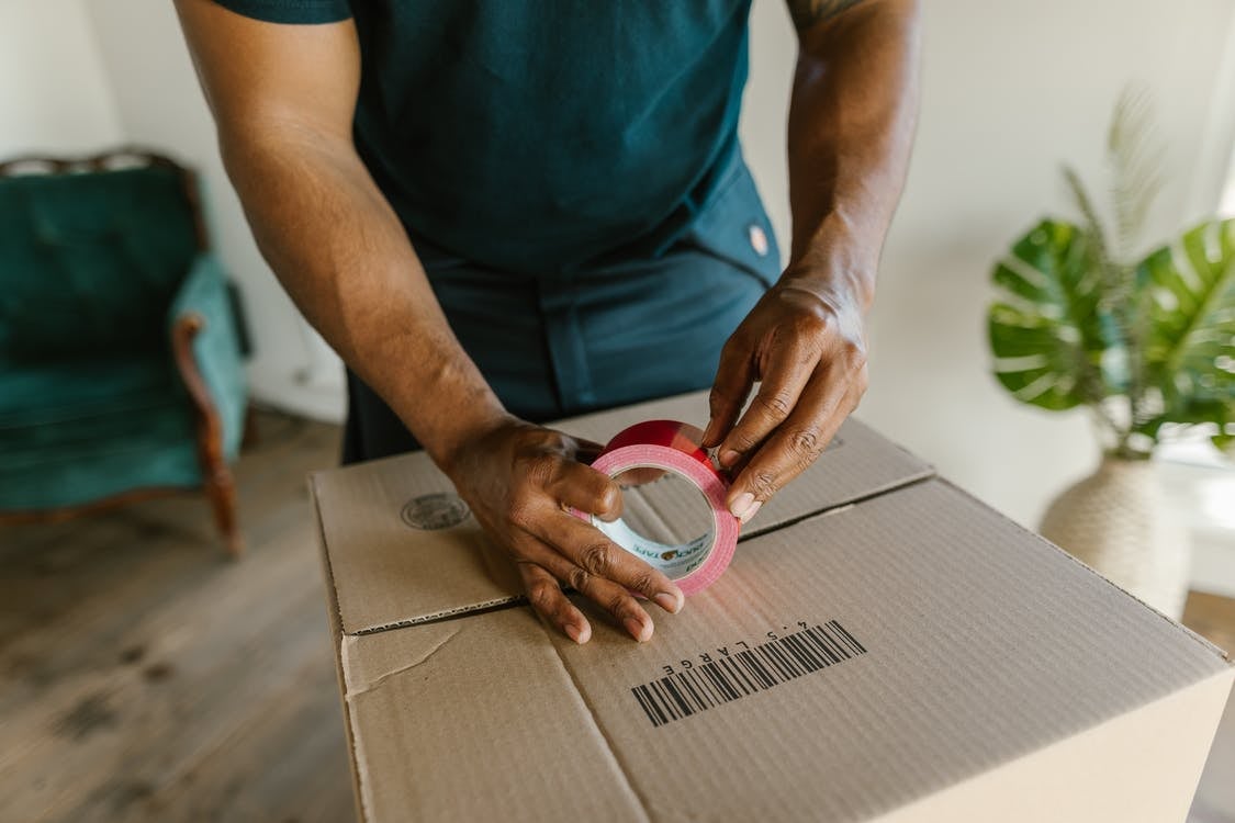 A man taping up a box in preparation for his individual move to Bangladesh.