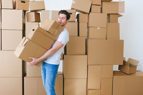 A man holds a box in front of a large stack of Atlas® International moving boxes.