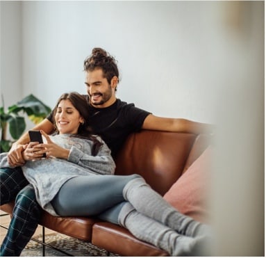 A man & woman enjoying each other's company on a cozy couch in a house they recently moved into.