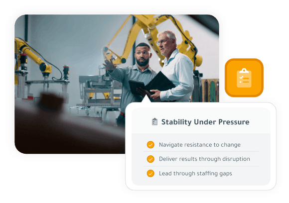 Two manufacturing employees stand on a factory floor near robotic arms, reviewing a clipboard and discussing operations. Overlay text reads “Stability Under Pressure” with points about navigating resistance to change, delivering results through disruption, and leading through staffing gaps.