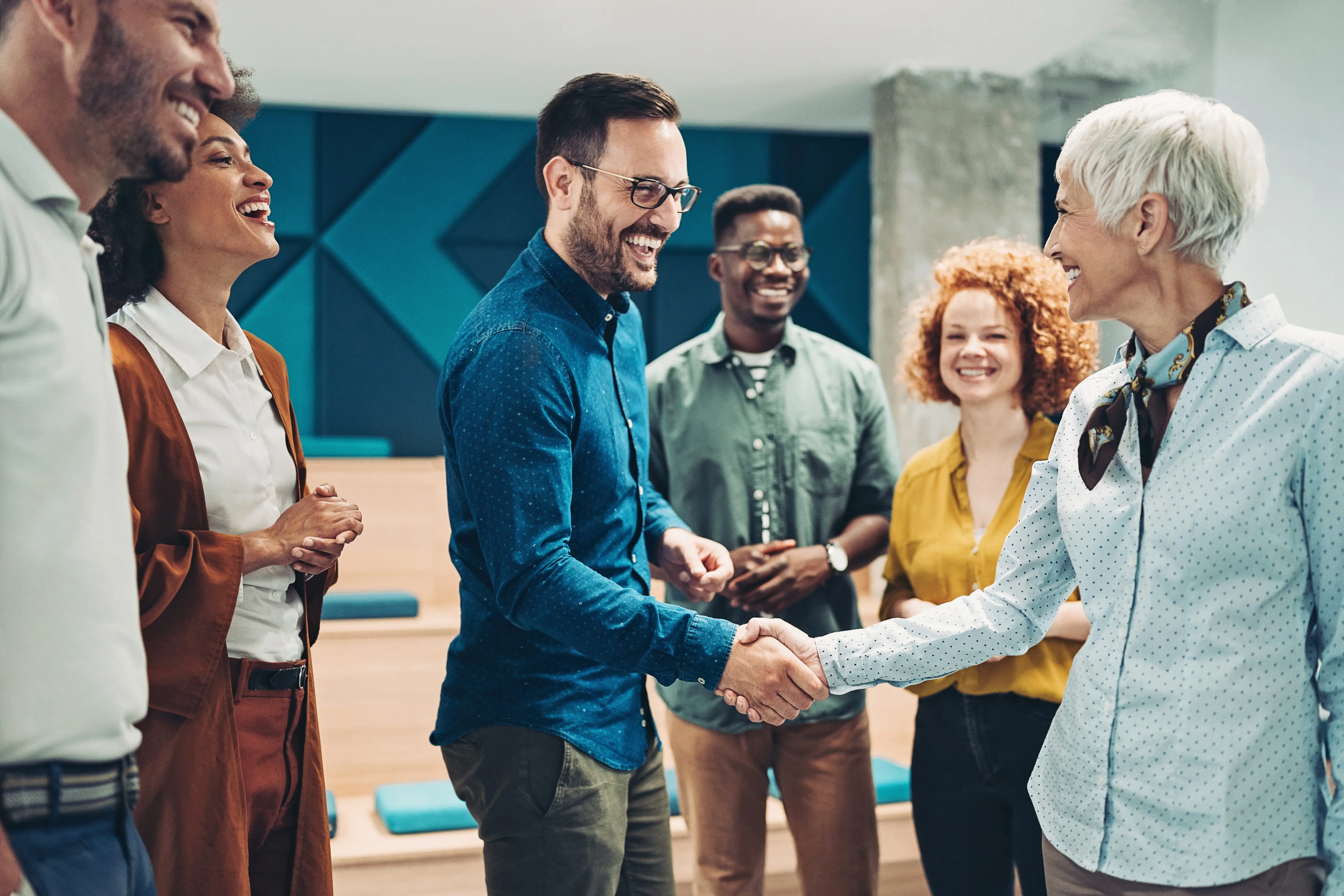 group of smiling leaders, all highly engaged with each other and two of the leaders are shaking hands