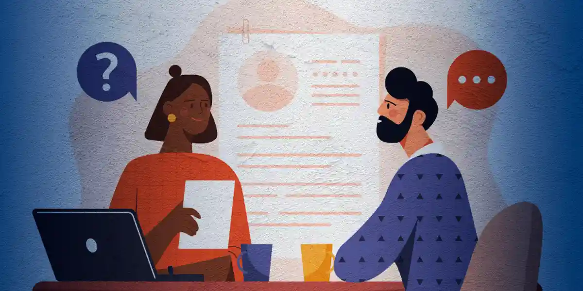 Ein Interviewer und ein Interviewpartner sitzen zusammen an einem Bürotisch, der Interviewer hält ein Blatt Papier mit verhaltensbasierten Interviewfragen in der Hand und der Befragte antwortet nachdenklich auf die Fragen des Interviewers