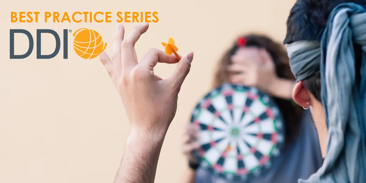 a blindfolded person throwing a dart at a dart board