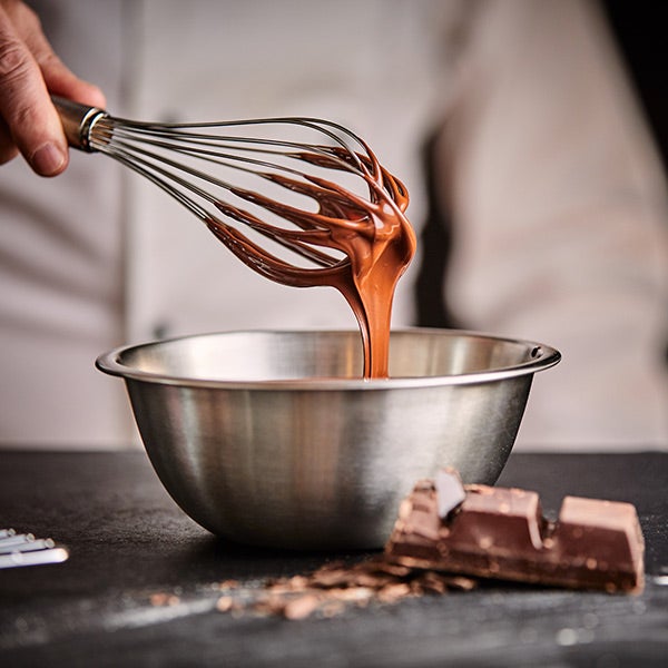 Chef mélangeant la sauce au chocolat dans un bol à mélanger.
