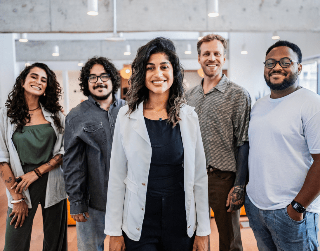 Groupe de collègues debout ensemble et souriants, représentant une organisation florissante fondée sur un leadership compétent.