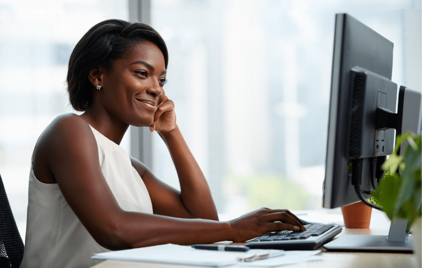 Leader souriant tout en tapant sur un ordinateur, représentant les solutions de leadership de DDI en action.