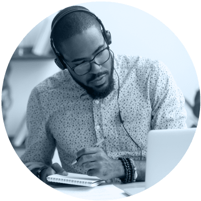 Un homme travaille sur son ordinateur portable avec des écouteurs pour montrer que l’apprentissage virtuel est le numéro 2 sur la liste des 10 sujets de leadership les plus brûlants pour 2021