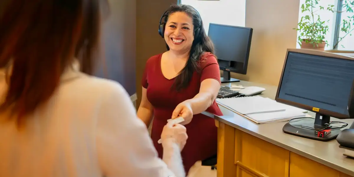 happy woman leader from Vantage Bank shown giving a client a credit card
