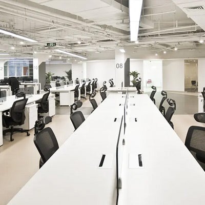 an empty office with long tables with computers missing