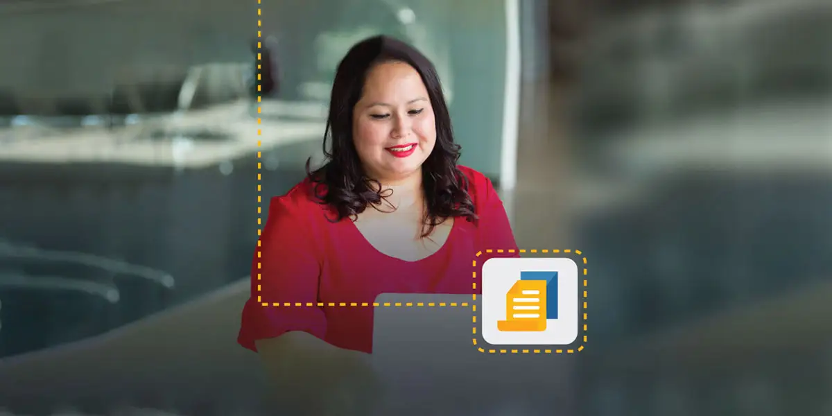 Une femme souriante regarde son ordinateur pour travailler sur un programme de développement du leadership des cadres