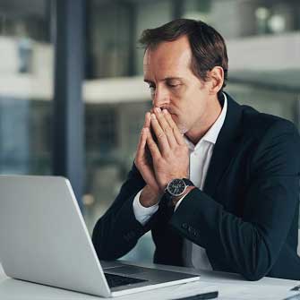 man sitting in front of laptop looking stressed about leadership development challenges