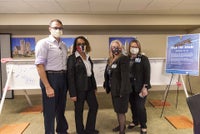 Team members pose in front of beam signing event.