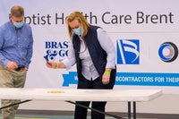 A woman handing a man a pen in front of a table