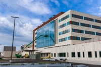 Crane working on glass panes on exterior of new campus building.