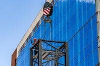 Crane holding metal piece in front of new campus building.