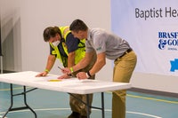Two men looking down at a table with a pen in their hand