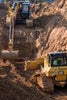Construction vehicles digging and leveling dirt.