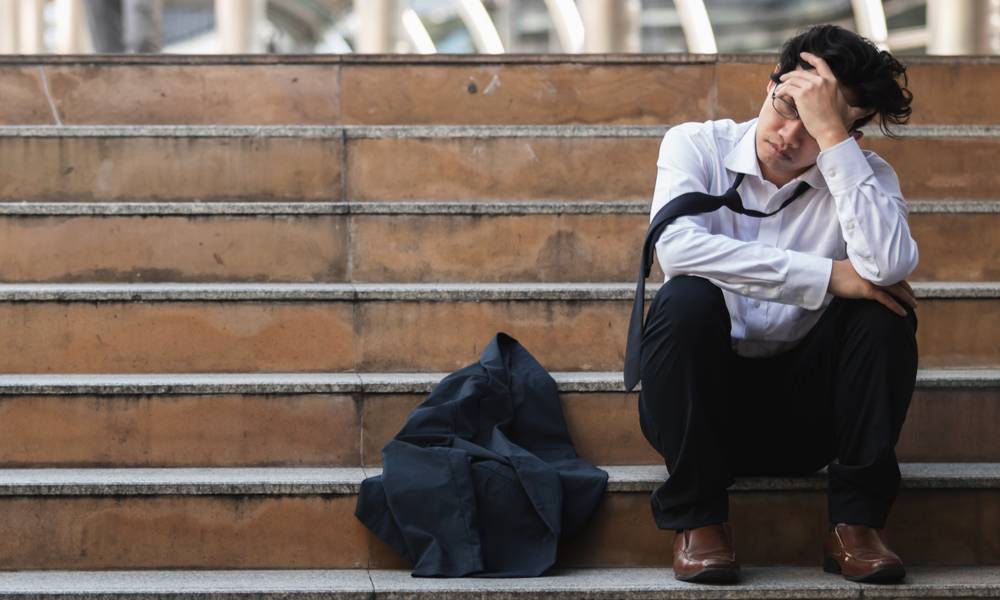 Unemployed stressed young Asian business man in suit covering face with hands (1).jpg
