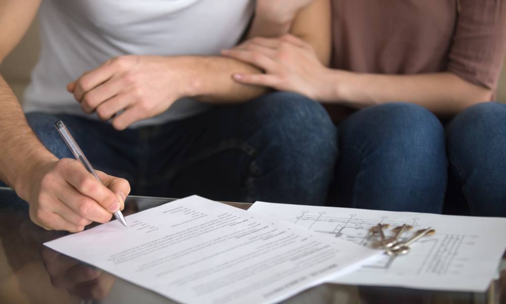 Close up of loving couple signing rental agreement or sale purchase contract sitting on couch indoors, starting family life, approved loan to buy real estate.jpeg