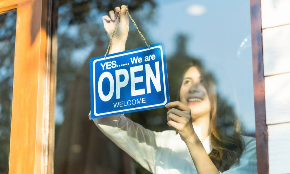 Woman hanging open sign outside bsuiness door (1).jpg