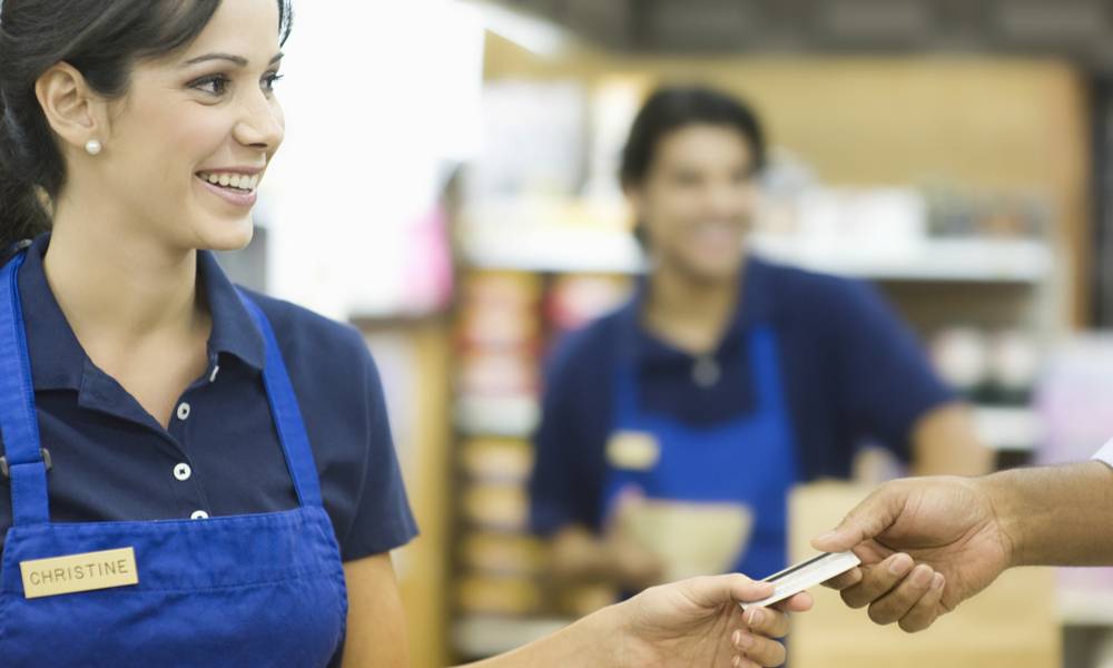 Closeup of a hand giving female employee loyalty card in supermarket (1).jpg
