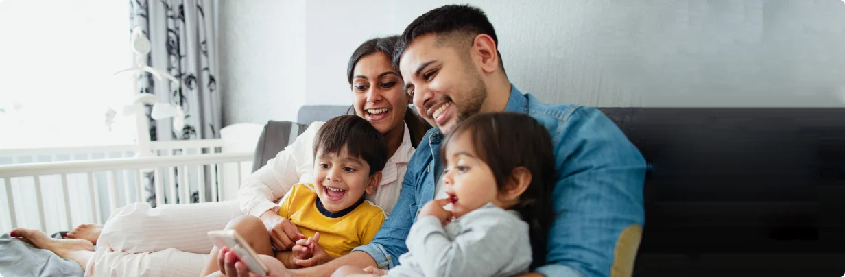 Family smiling and laughing at a phone.