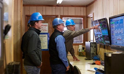 group of men talking discussing information on a digital screen