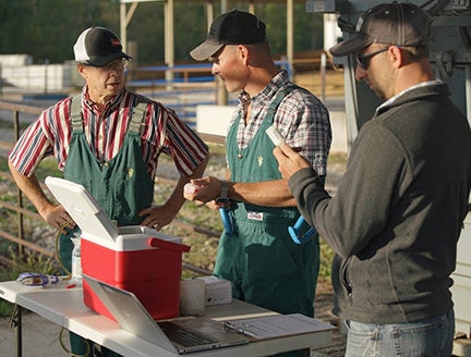two veterinarians talking to each other with a man stood next to them