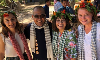 three women with flower arrangements on their head smiling with a man