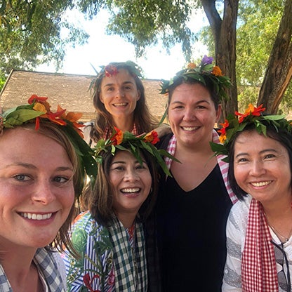 five women smiling at the camera with flower arrangements on their heads

