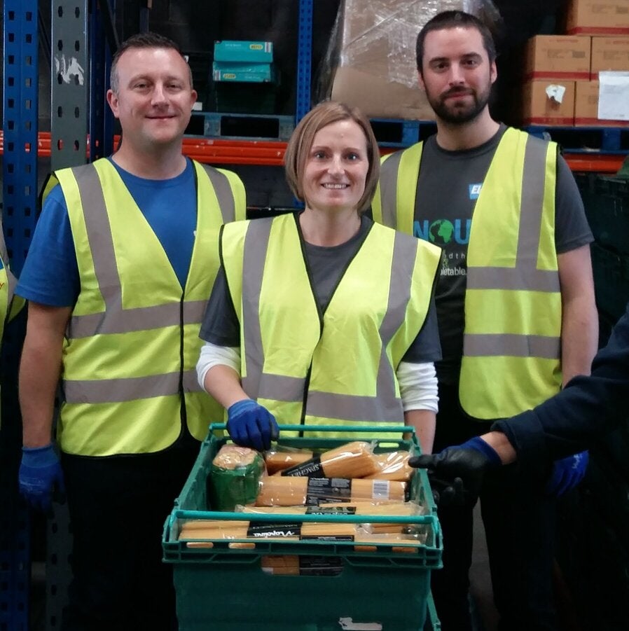 employees standing together while holding a basket of food