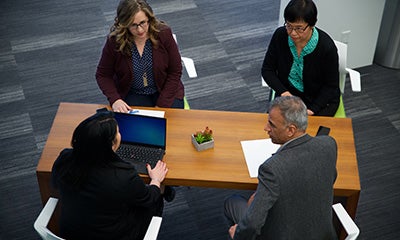 overhead view of three women and a man discussing at a table