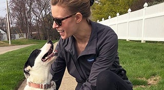 close up of a woman and a dog looking at each other on a sidewalk